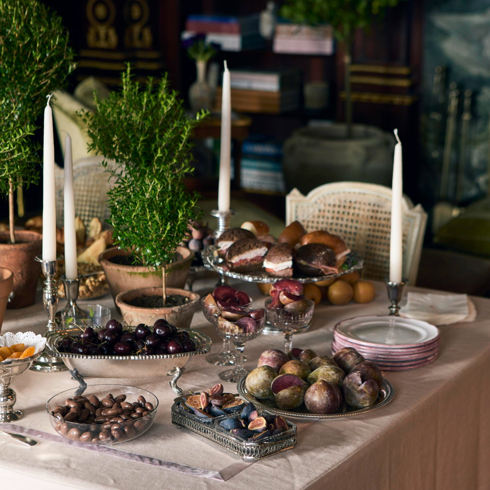Rustic dessert table with figs and pastries on linen, warm candlelit setting