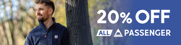 20% OFF ALL PASSENGER. A smiling man leans against a tree, wearing Passenger Men's Woodland Hoodless 2.0 1/2 Zip Fleece in Navy.