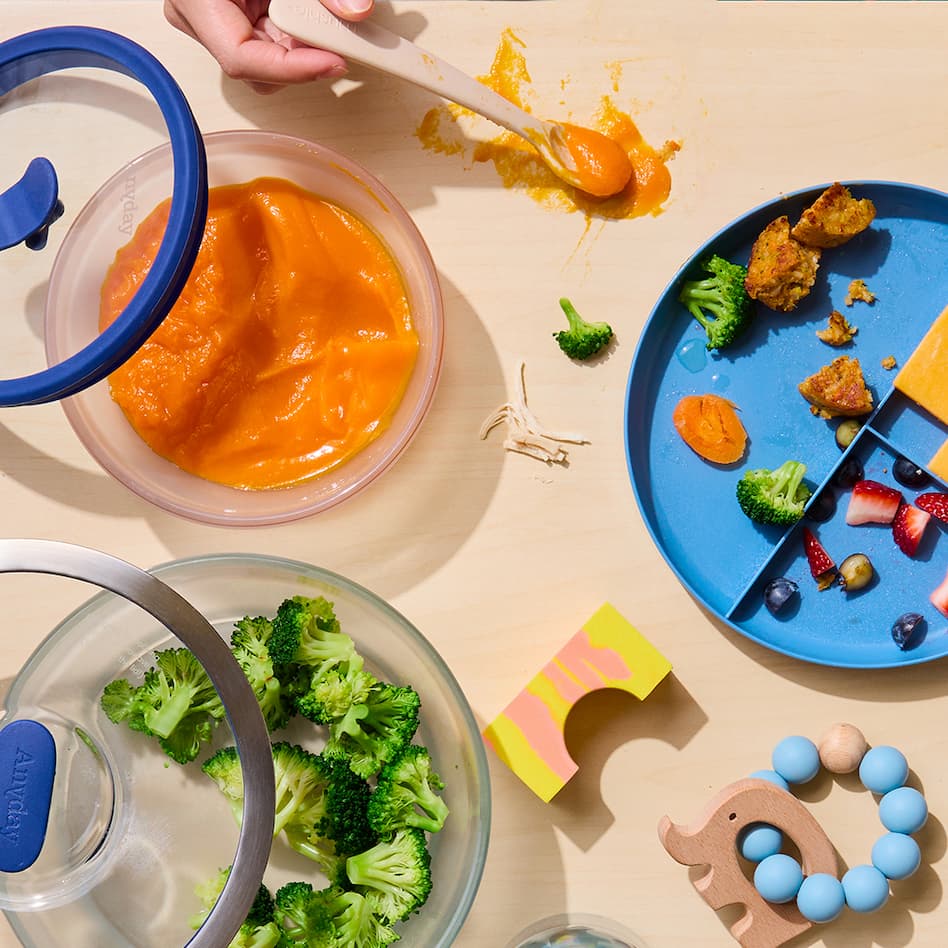 Anyday dishes filled with broccoli and sweet potatoes with kid plates and toys.