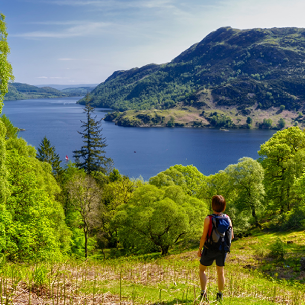 A walker looking out towards a lake in the Lake District