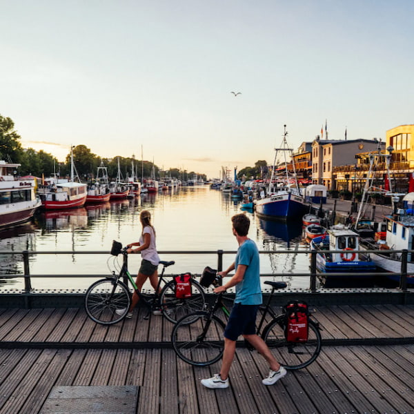 A cyclist at a harbor on the Baltic Sea coast at sunset