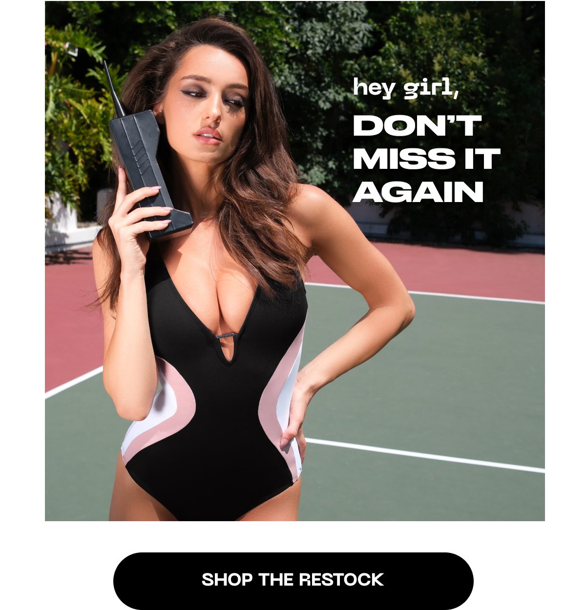 Woman in a swimsuit holding a vintage phone on a tennis court.