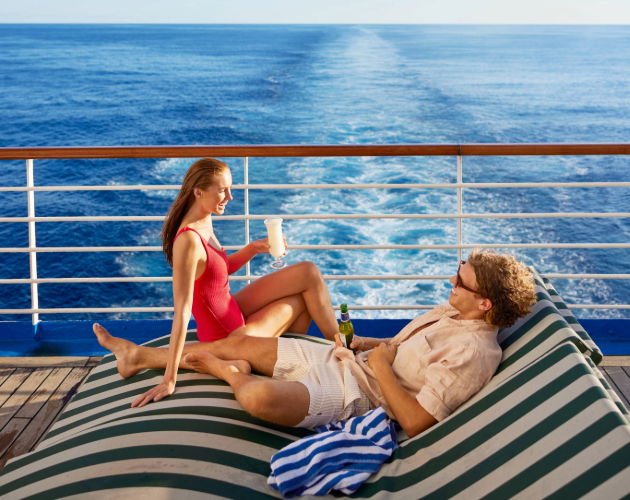 A couple laying on sunbeds on a cruise ship