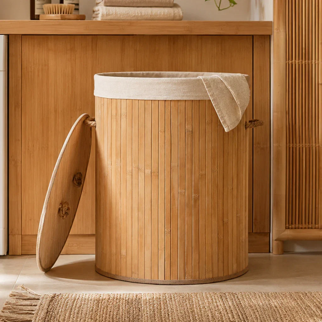 Bamboo laundry hamper with cream linen interior and matching lid in minimalist bathroom setting