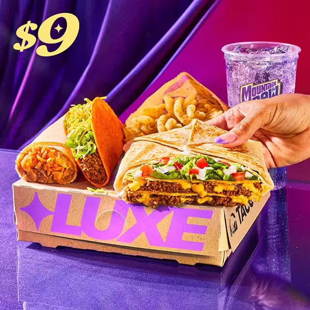 A Discovery Luxe Box on a purple table with a person holding up the Triple Double Crunchwrap®.