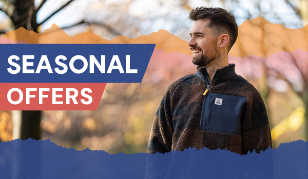 SEASONAL OFFERS: A man walks through the woods wearing Passenger Men's Offroad Sherpa 1/2 Zip Fleece in Navy/Brown.