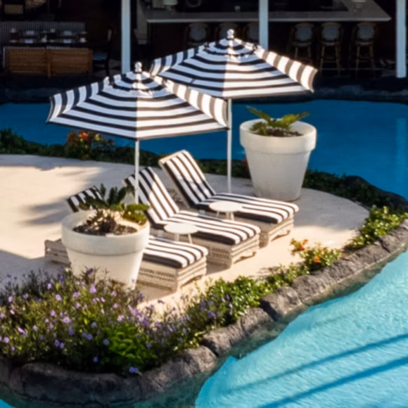 Loungers by the swimming pool at Colony Club resort in Barbados, linking to BA High Life site.