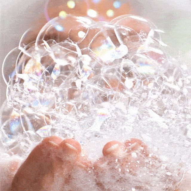 Person blowing bubbles from their hands.