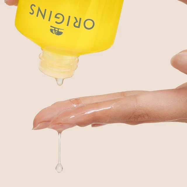 Bottle of Checks and Balances™ Milky Oil Cleanser + Makeup Melter dispensing liquid onto an outstretched hand.