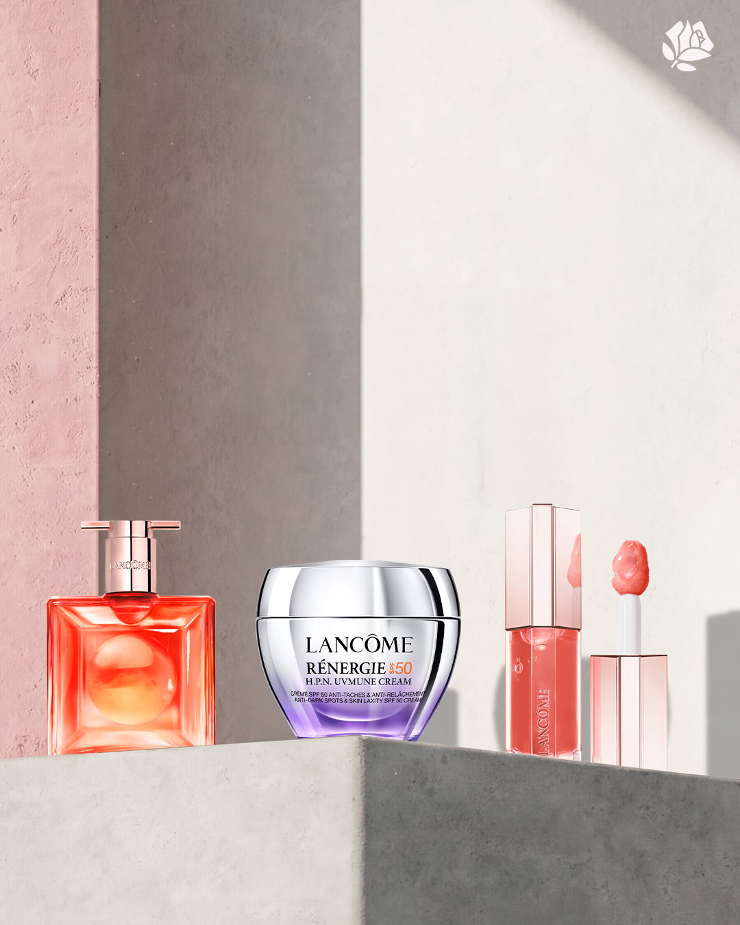 Tre prodotti Lancôme su mensola: profumo Idôle Peach'n'Roses, crema Rénergie SPF50, e un lip gloss rosa cipria.