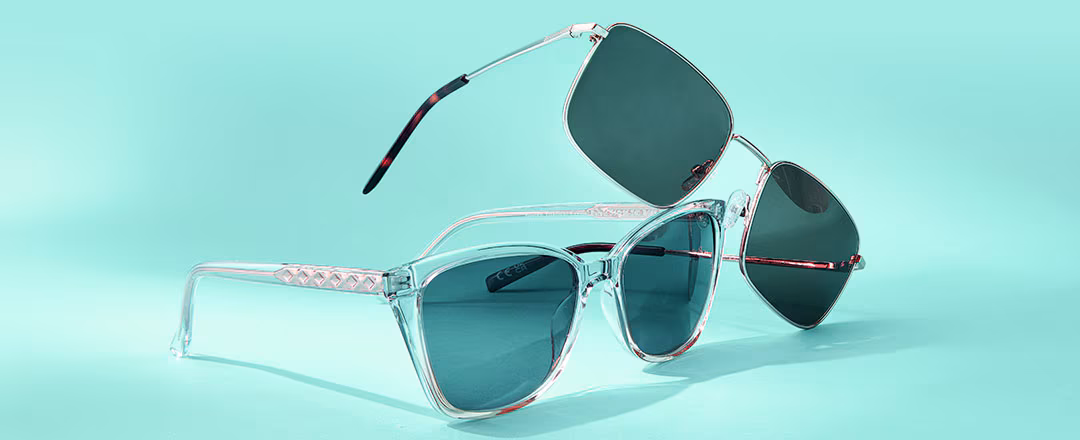 Two pairs of sunglasses, one clear-framed and one dark-framed, on a teal background