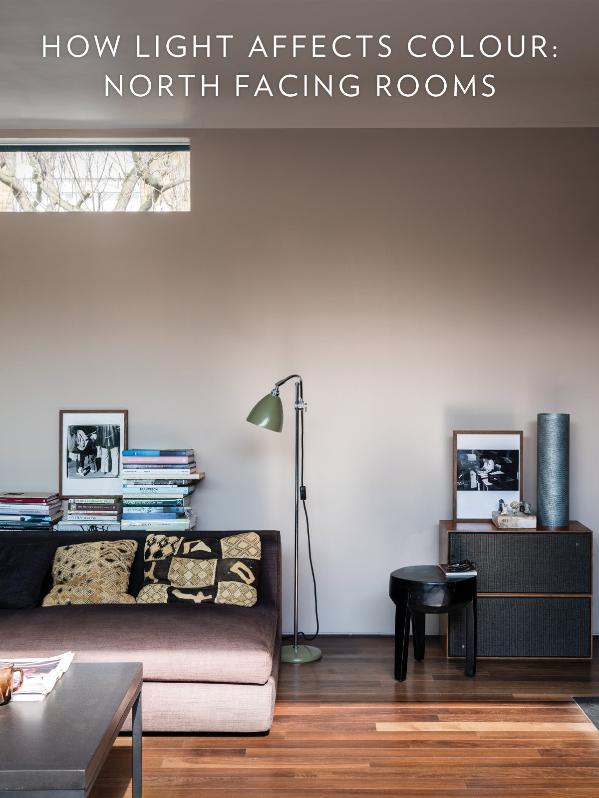 A relaxed living room, where low-level seating, stacked books and warm wood tones give an easy, laid-back feel. Soft light drifts across neutral walls to create a space that feels calm and inviting.