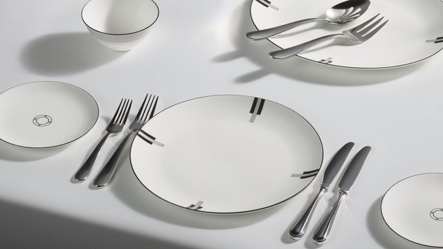 White tabletop with the new Vera Wang Luxe Graphite tableware pieces dispayed for mealtime. A mix of dinner plates, rice bowl , bread and butter side plates, and silver cutlery.