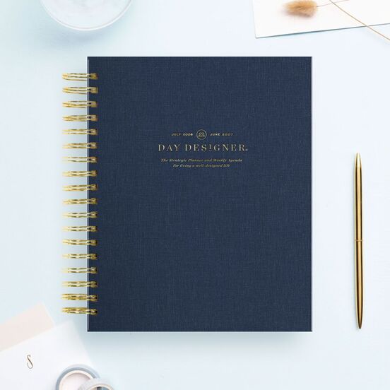 navy bookcloth day designer planner, gold binding and pen, stationery, light blue background