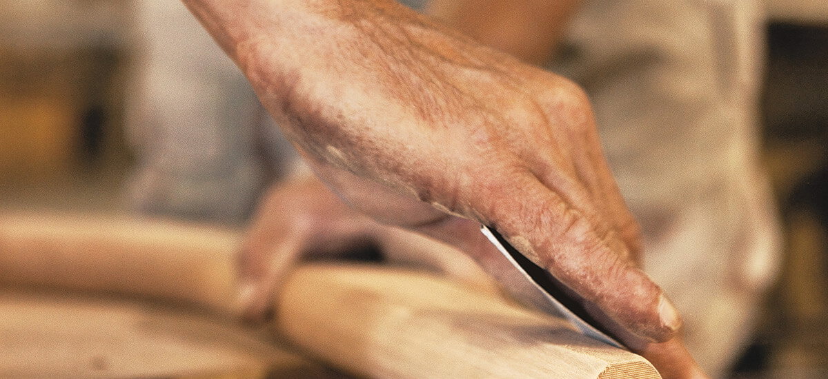Closeup of a craftsperson's hands sanding a piece of wood.