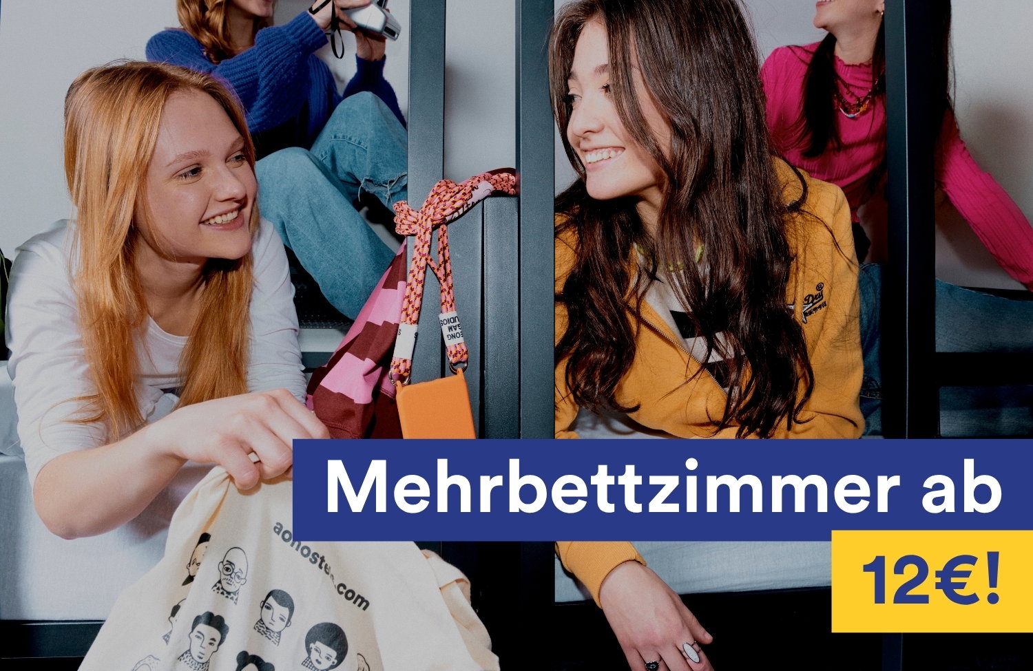 Zwei junge Frauen sitzen lachend in einem Mehrbettzimmer eines a&o Hostels. Im Bild ist der Text „Mehrbettzimmer ab 12 €!" eingeblendet.