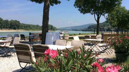 Hotel Gastgarten mit Stühlen und Tischen und Blick auf die Donau