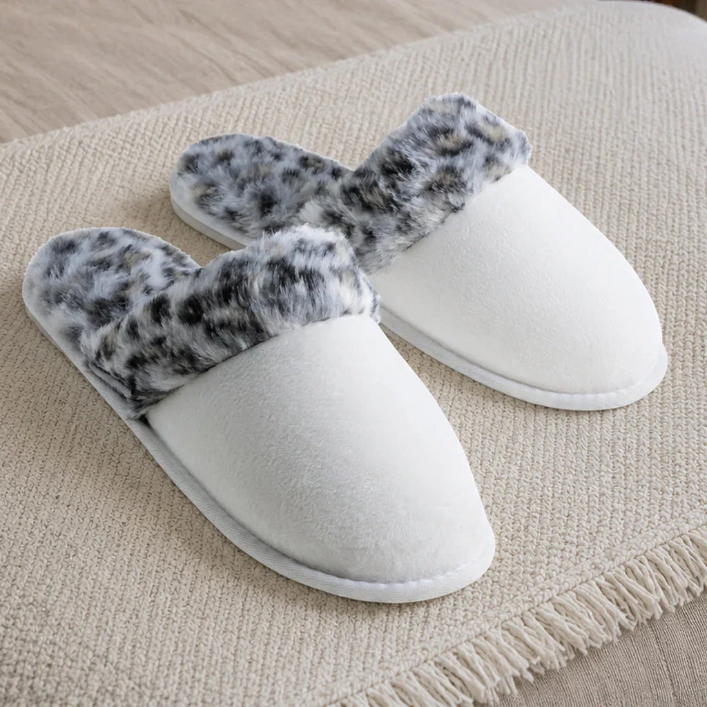 Pair of white plush slippers with gray leopard print lining on a cream-colored fabric surface.