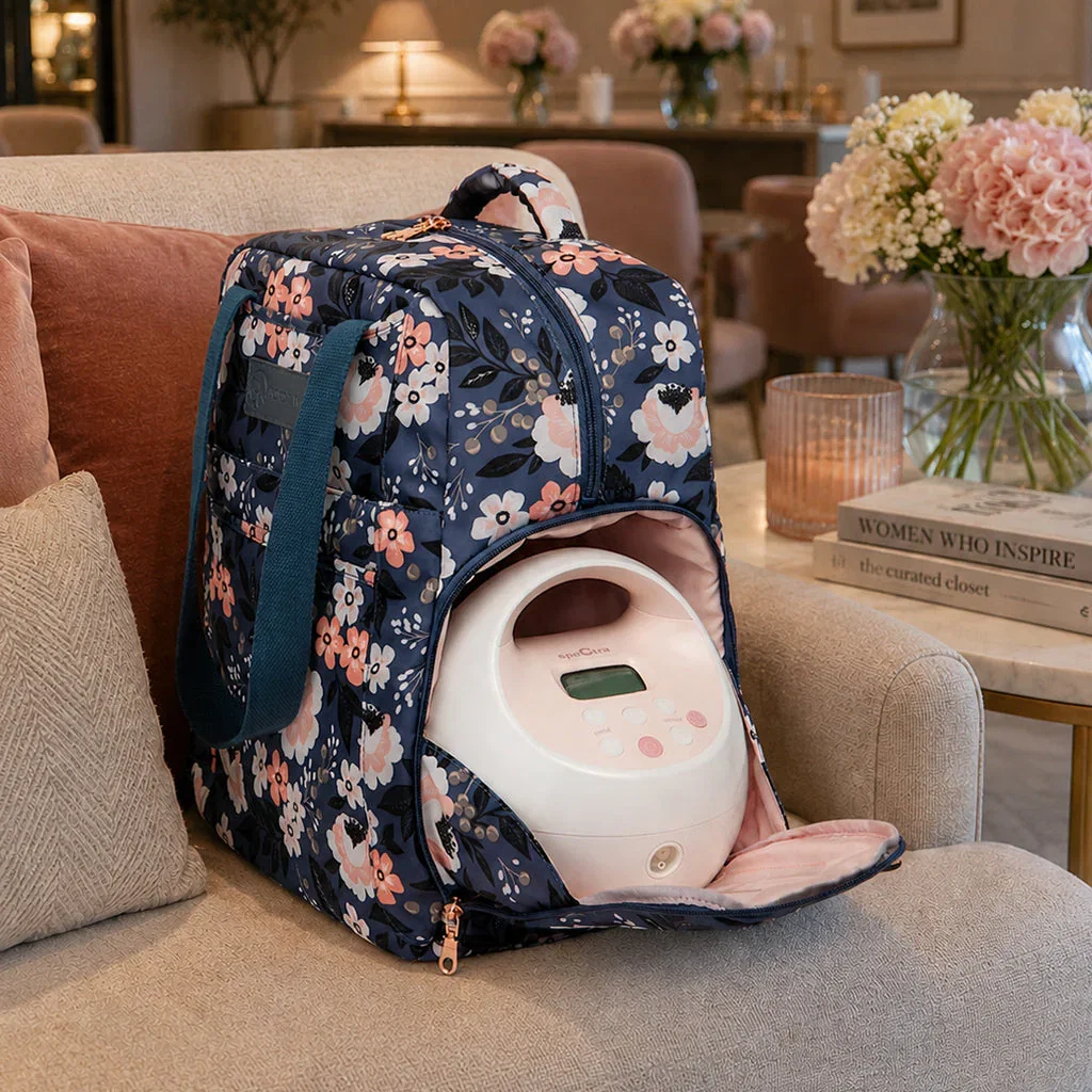 Sarah Wells floral backpack with white breast pump displayed on beige sofa in elegant living room setting