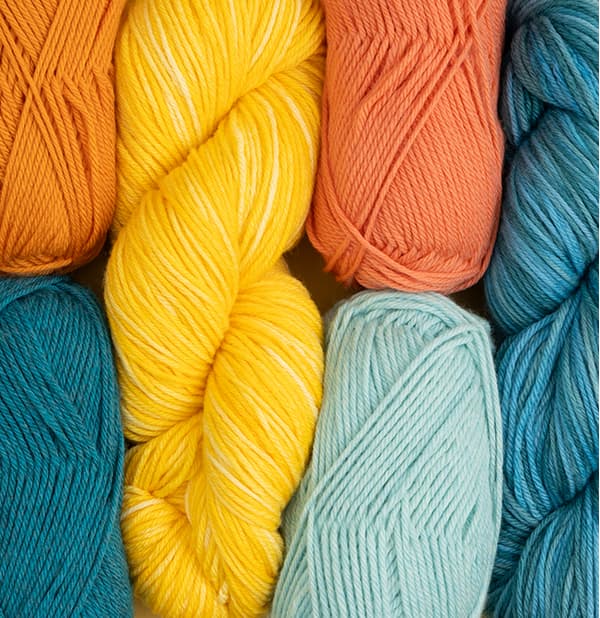 Skeins of sock yarns in aquas, oranges, and yellows. >>