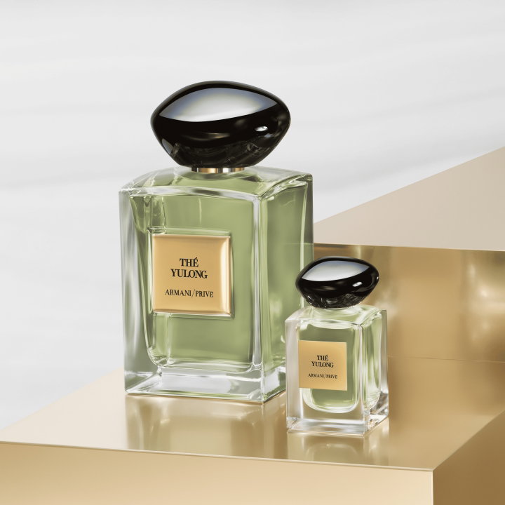 Dos frascos de perfume Armani Privé Thé Yulong de distintos tamaños están presentados sobre una superficie dorada reflectante.