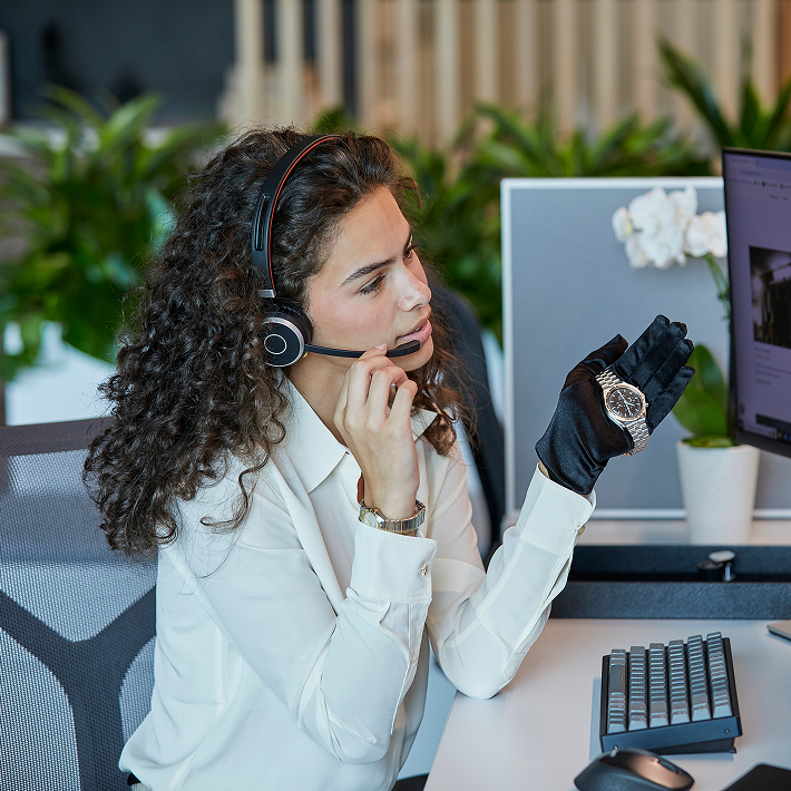 Client services representative speaking with client on virtual boutique call while holding watch