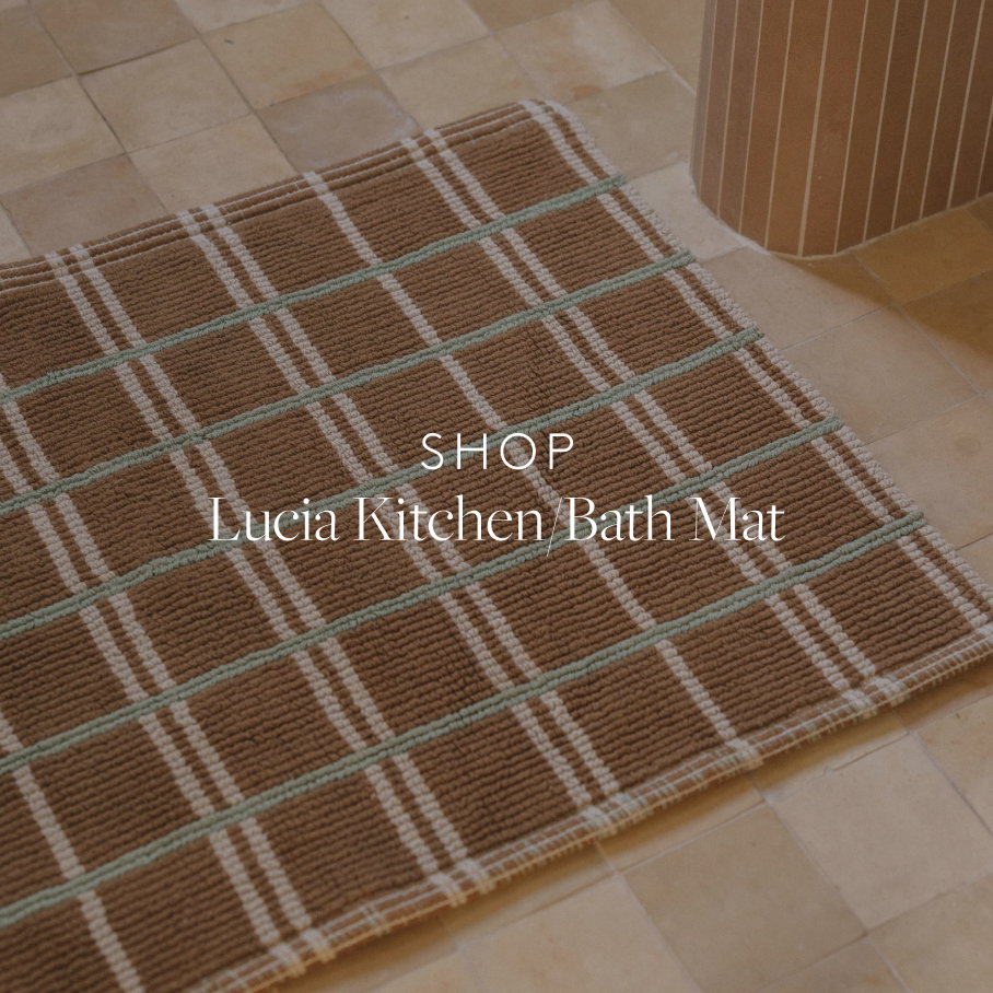 Brown bath mat with teal and cream checks on a tile floor