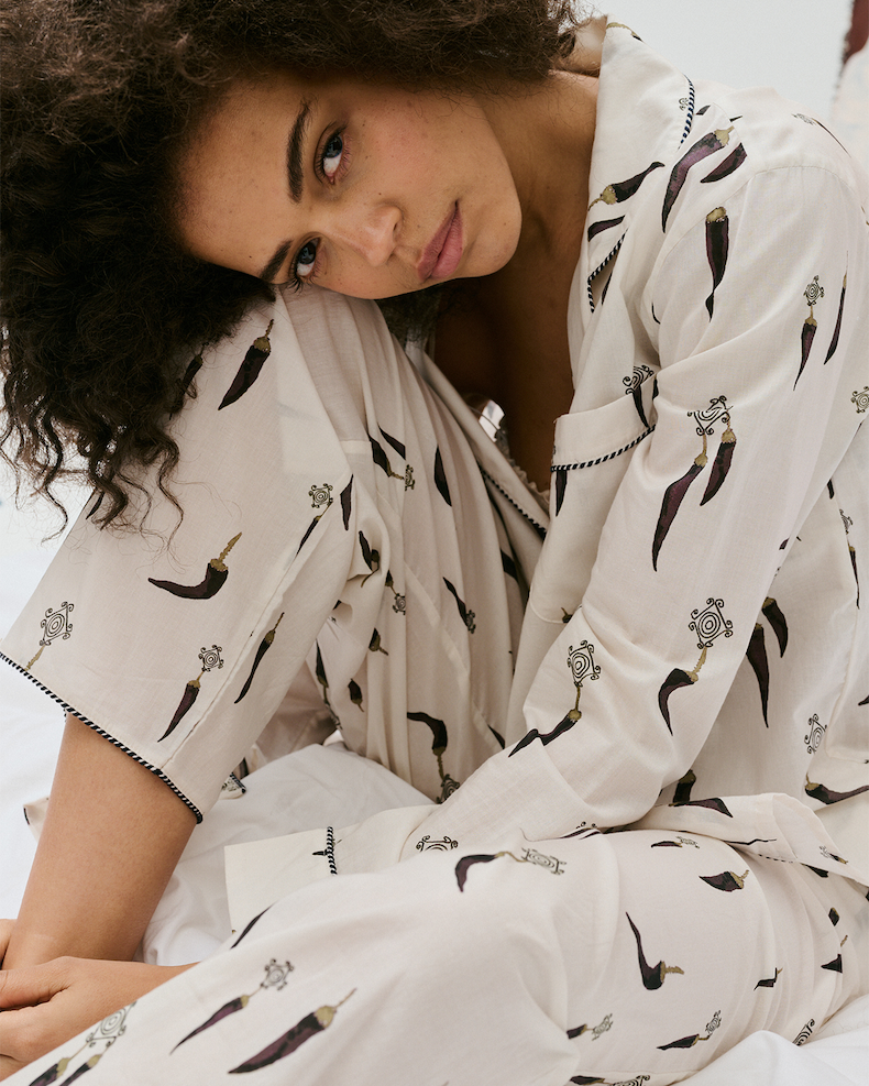 A model sitting on white sheets in the Picante Cream pyjama set.