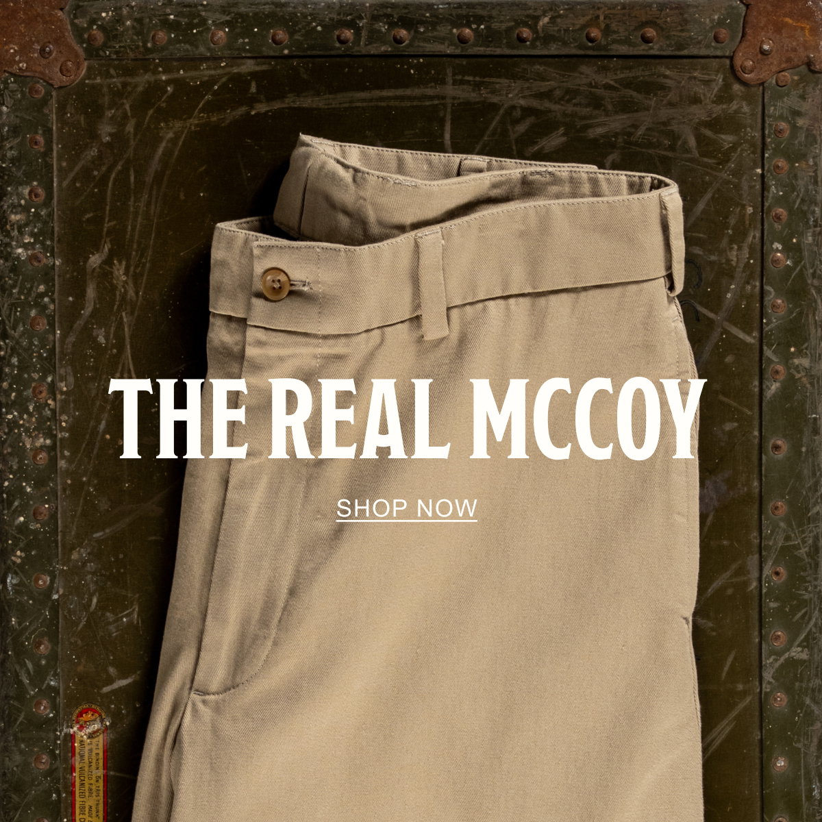 A pair of Bills Khakis Original Twill M1 Khakis on a vintage green chest. Text reads: The Real McCoy | Shop Now