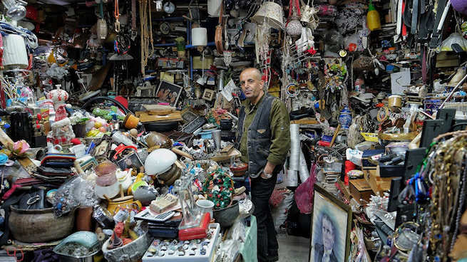A man standing in a very, very, very cluttered room
