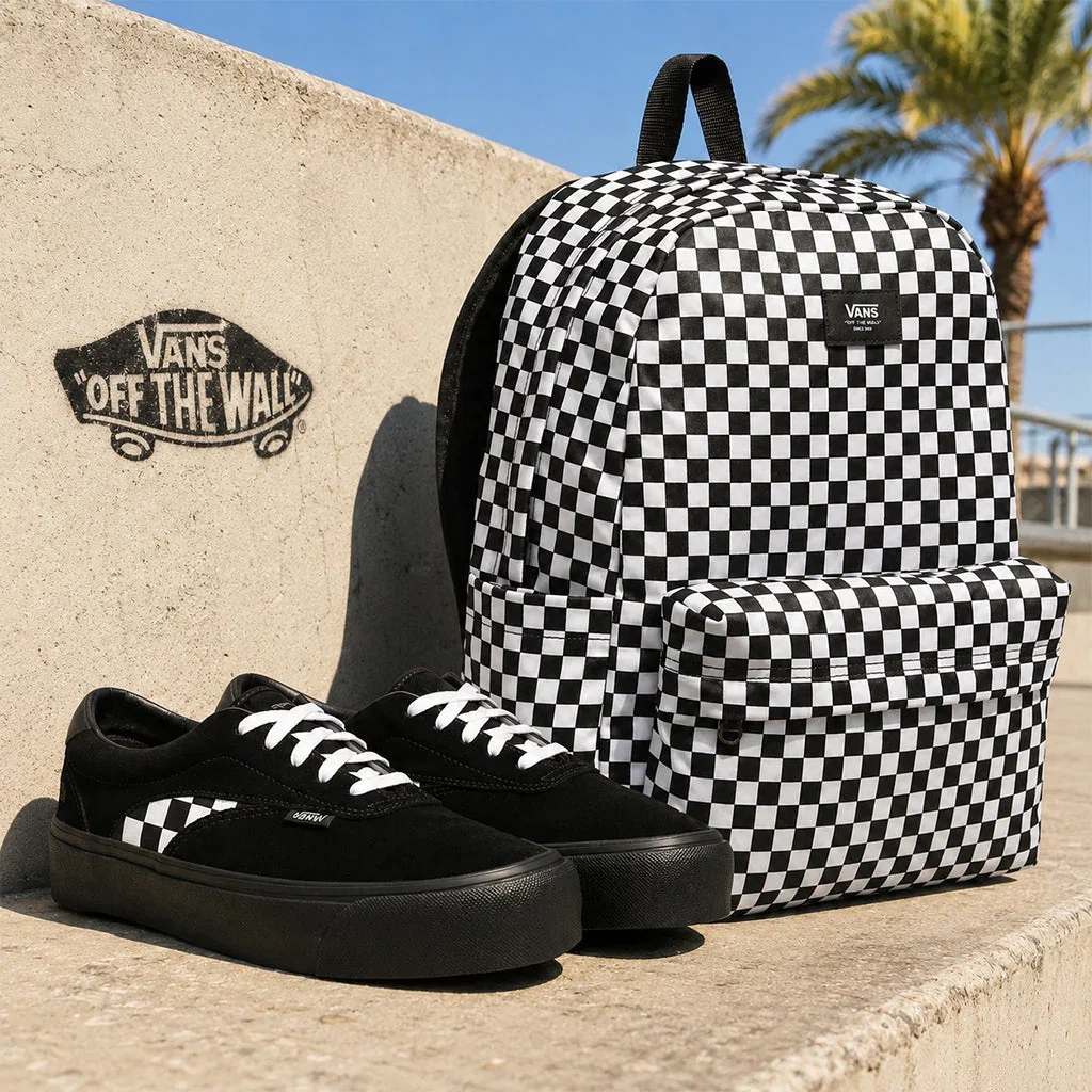 Vans black and white checkerboard backpack with matching platform sneakers displayed against a concrete wall with Vans logo.