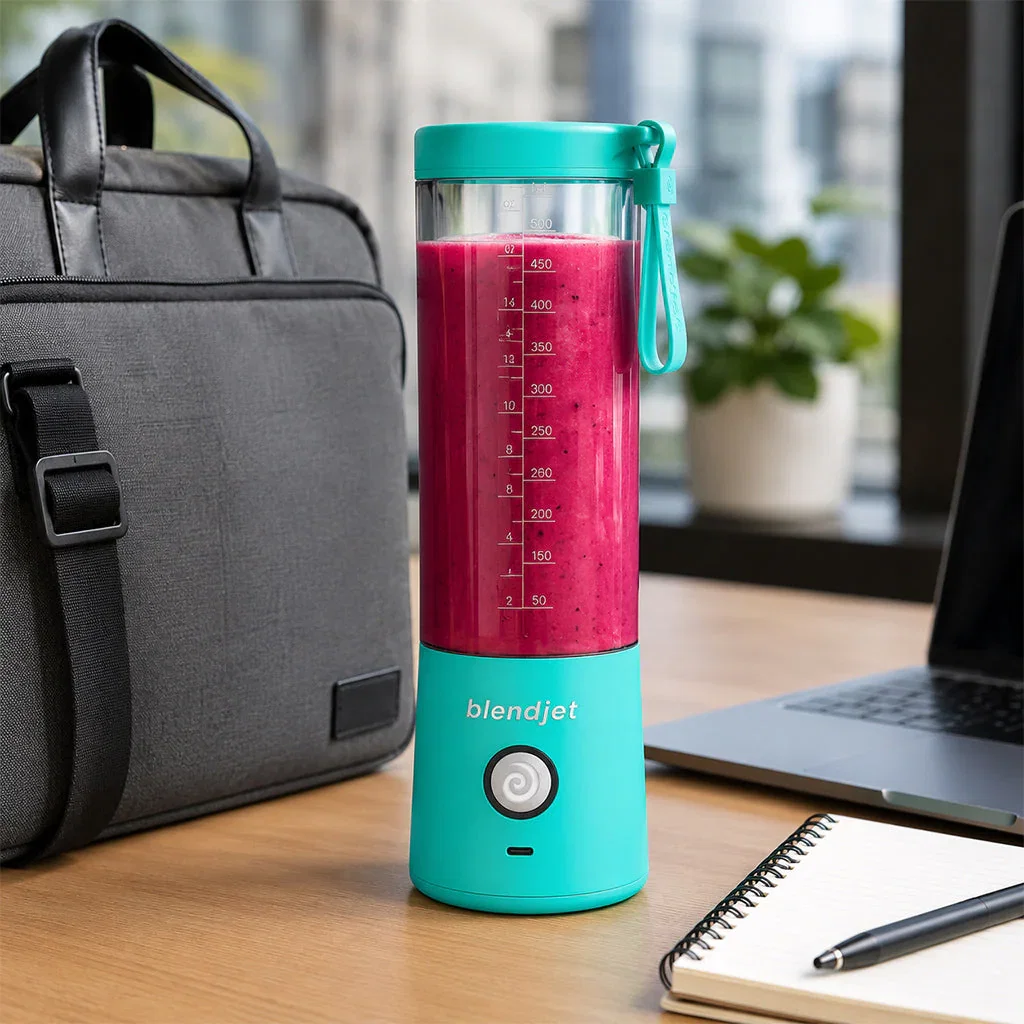 Turquoise Blendjet portable blender filled with pink smoothie on office desk with laptop and notebook