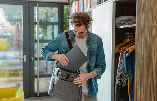 Une personne mettant son ordinateur portable XPS 14 DA14260 dans son sac pour ordinateur portable à la maison.