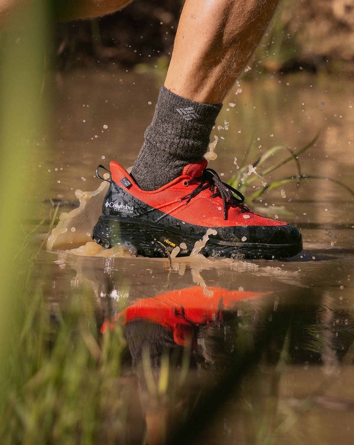 Close up of a muddy hiking shoe running through mud