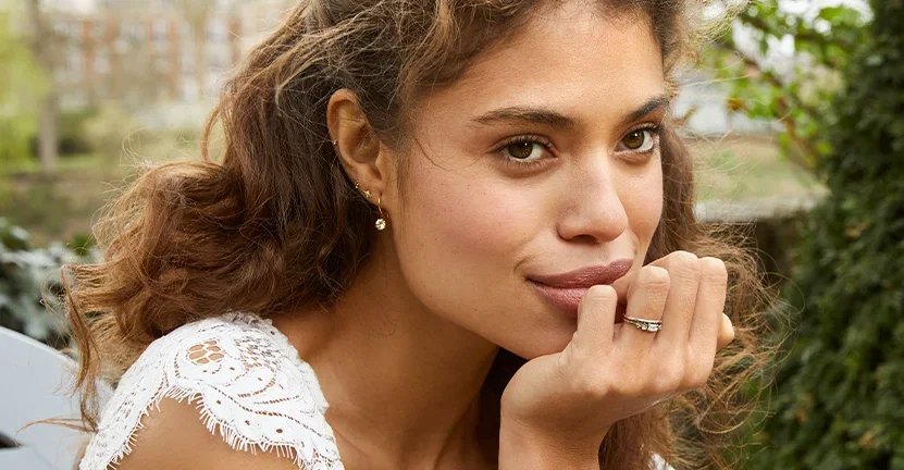 Model wearing an Alex Monroe white gold diamond engagement ring paired with a matching wedding band