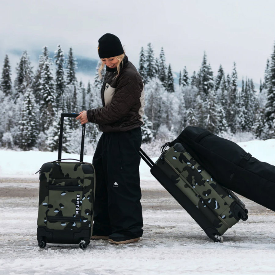Burton Team Rider, Ylfa Runarsdottir, on a snow covered road with the 4-Wheel Flight Deck 38L, 4-Wheel Double Deck 86L, and a wheelie snowboard bag.