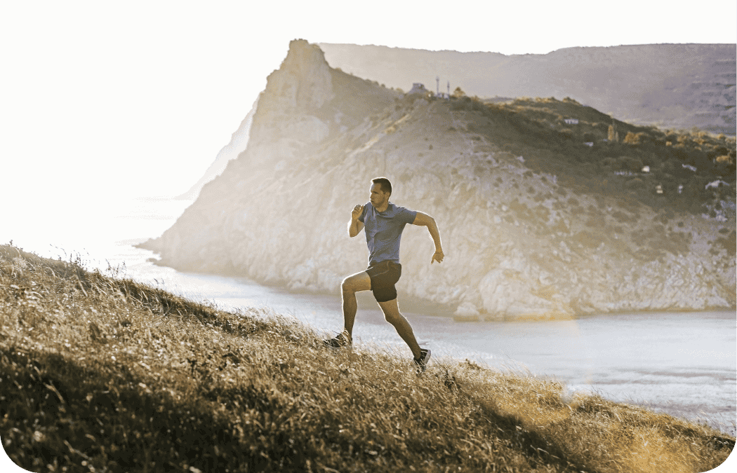 man running up a hill with the sea in the background