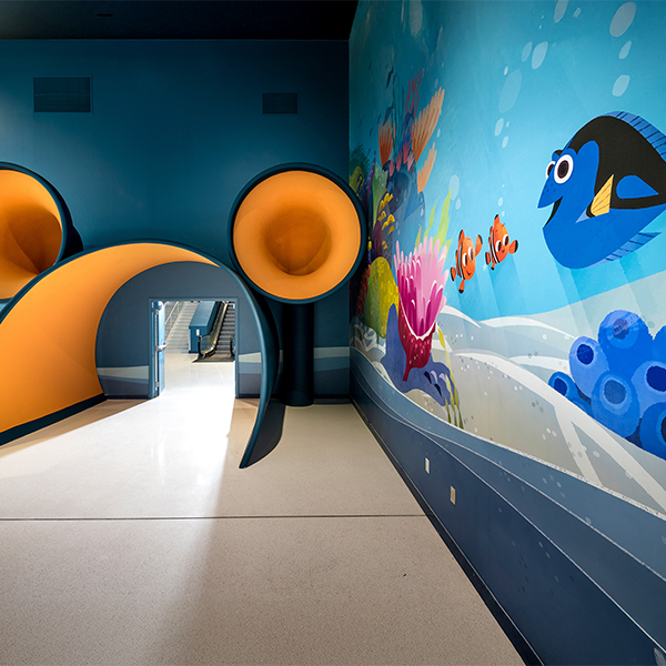 A smiling Dory in a Finding Nemo mural leads to a Mickey Mouse-shaped tunnel Guests use to board their Disney cruise.