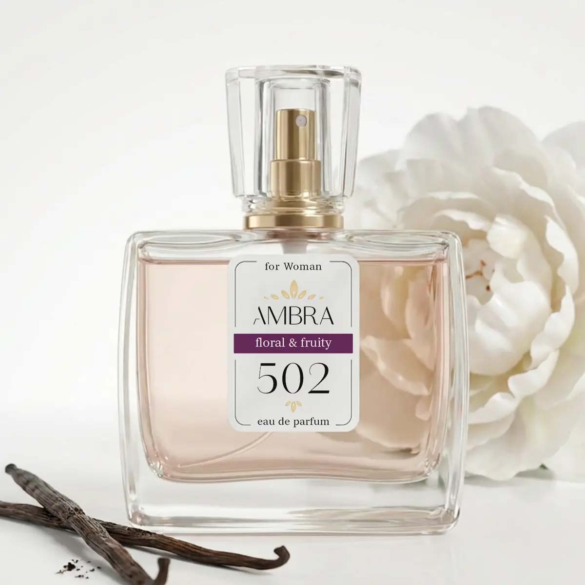Clear glass bottle of AMBRA 502 floral & fruity eau de parfum for women, pale pink liquid beside a white peony and vanilla pods