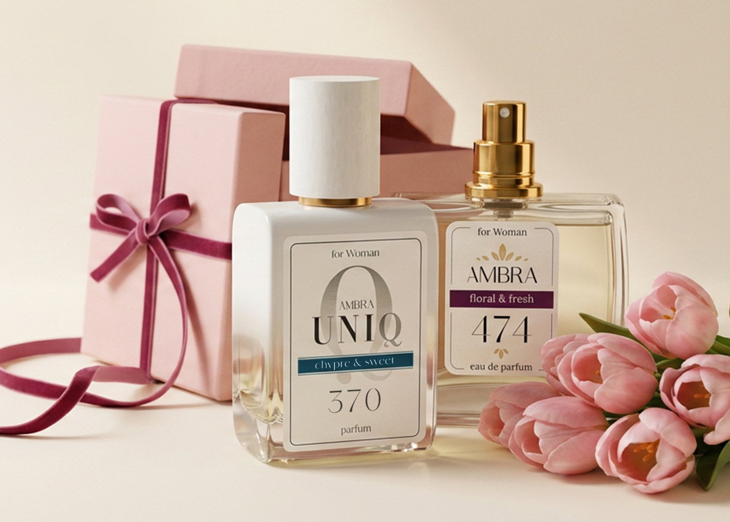 Two Ambra perfume bottles (UNIQ 370 and 474) beside pale pink gift boxes tied with a ribbon and a bunch of pink tulips