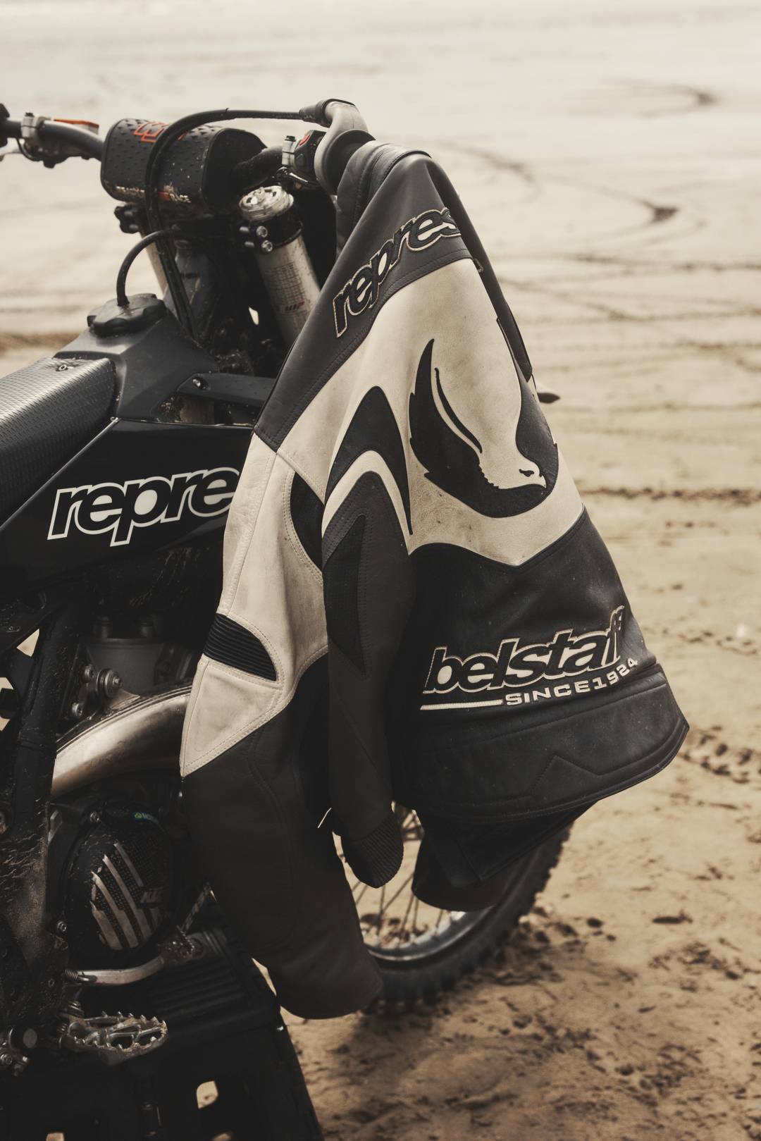 Represent x Belstaff Leather Race Jacket hanging on a branded motorcross bike