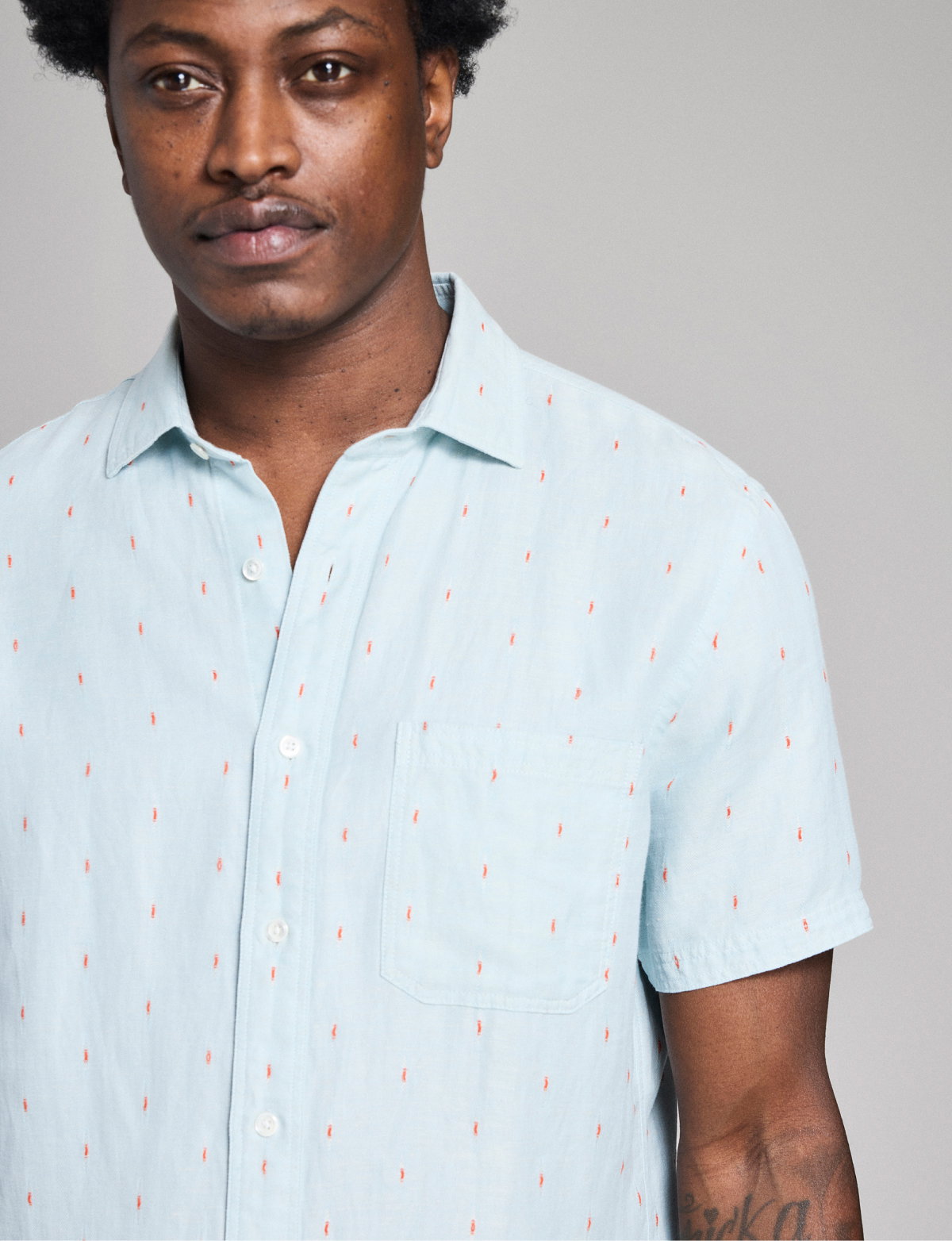 Model wears the Short Sleeve Herringbone Treme Shirt in Sky Blue on a grey background.