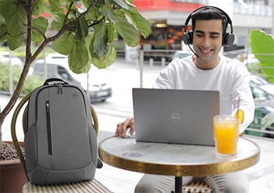 Man with a Dell EcoLoop Urban Backpack, Inspiron 15 laptop and ro Wireless Headset. 
