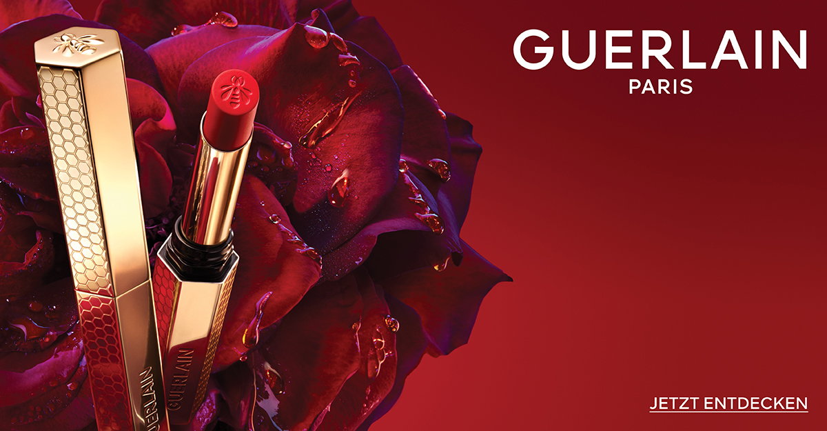 Guerlain Paris Lippenstift mit goldener Hülle und roter Farbe vor einem Hintergrund aus roten Rosenblüten, jetzt entdecken