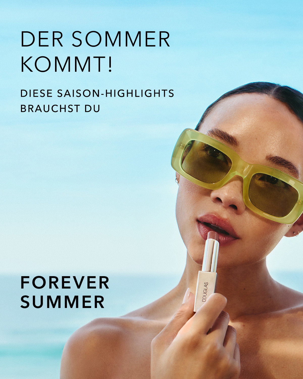 Werbemotiv vor blauem Himmel und Meer: Eine Person trägt große, rechteckige Sonnenbrille und hält einen Lippenstift an die leicht geöffneten Lippen. Auf dem Bild steht der Text „DER SOMMER KOMMT! DIESE SAISON‑HIGHLIGHTS BRAUCHST DU“ sowie „FOREVER SUMMER“.