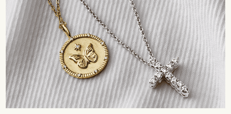 A gold medallion pendant with a butterfly design and a white metal diamond cross pendant. 