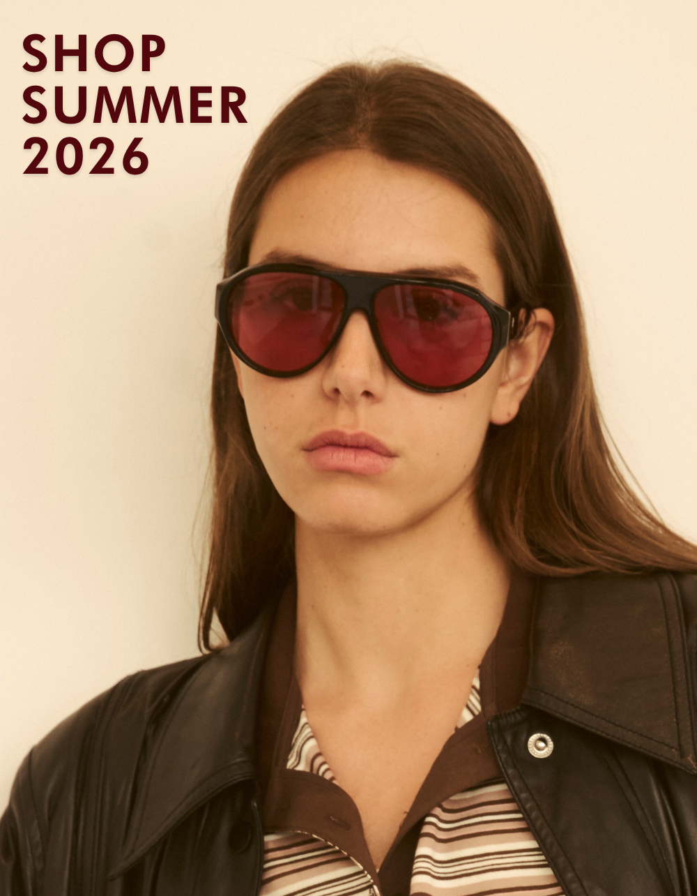 A portrait of a woman wearing a black leather jacket over a striped polo shirt. She is wearing the Telluride sunglasses with deep red/pink tinted lenses. Bold text in the corner reads: 