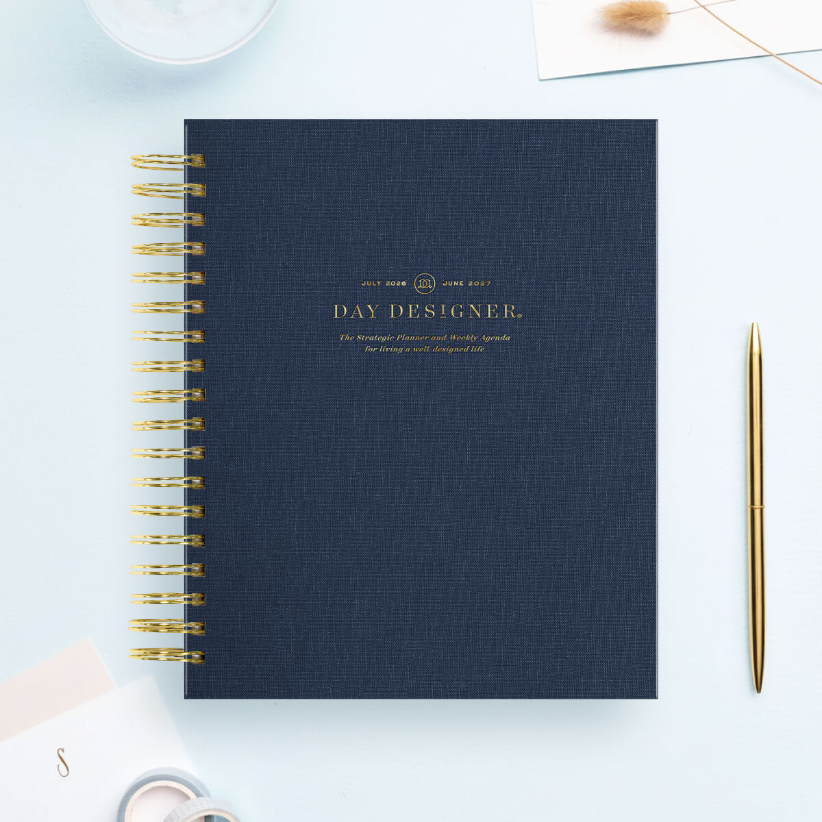 navy bookcloth day designer planner, gold binding and pen, light blue background, stationery