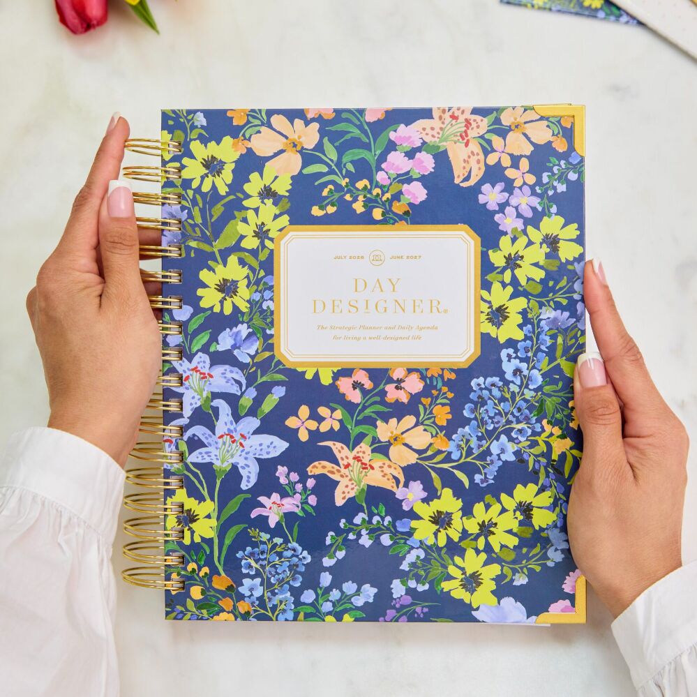 hands holding pretty navy floral day designer planner, pink flower, white background