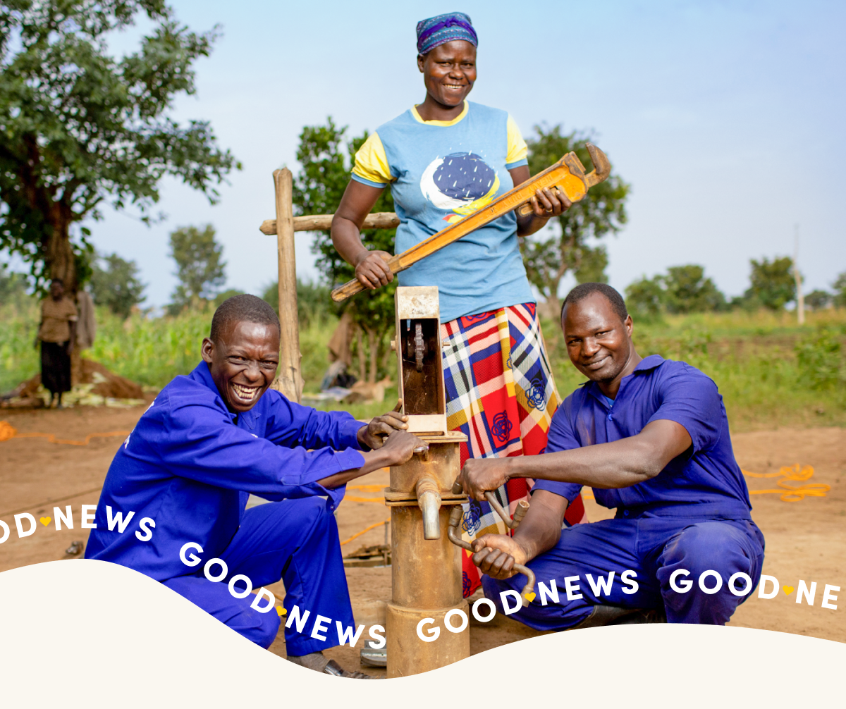Three men smile at the camera as they install a sensor at a water point.